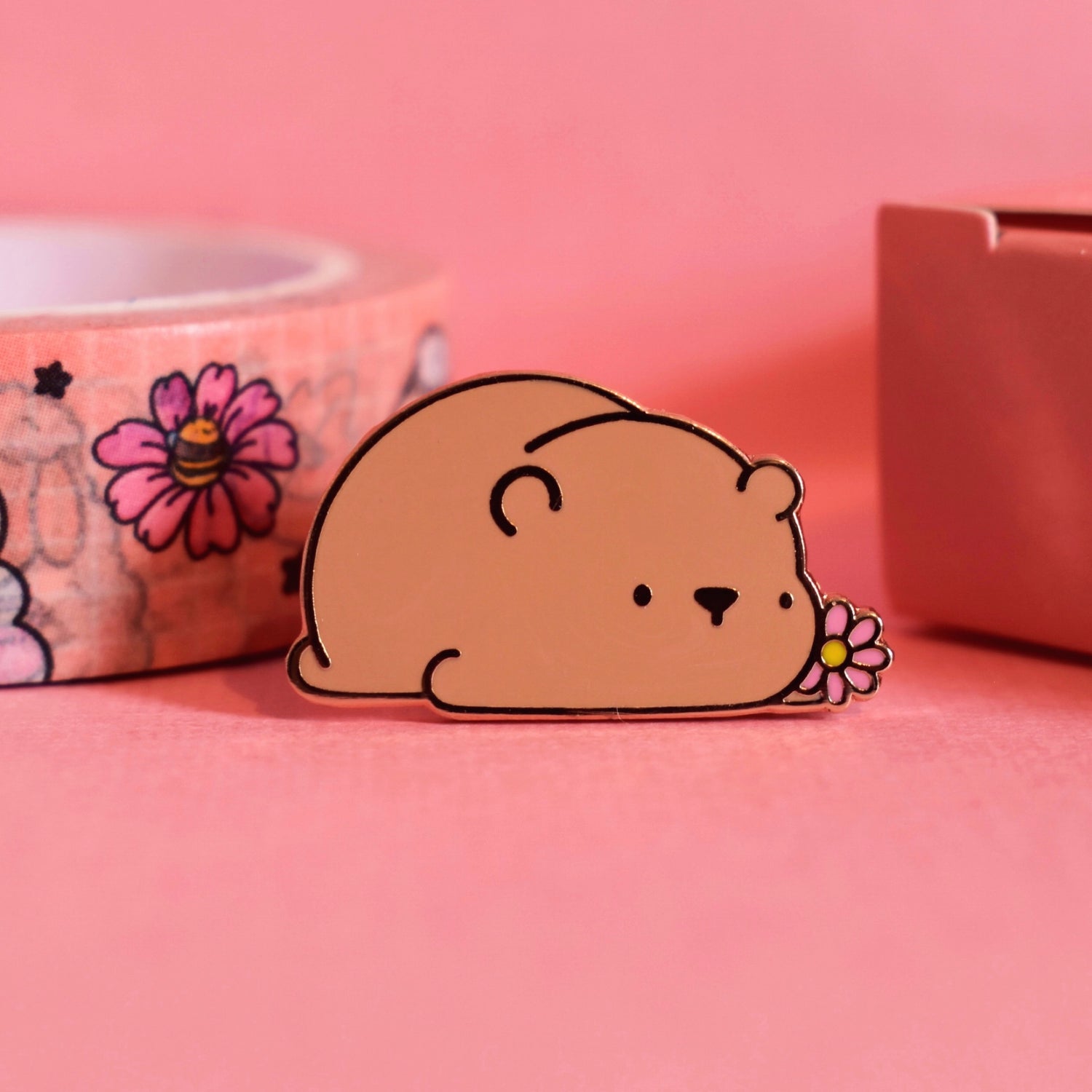 Brown bear enamel pin on pink table with washi tape