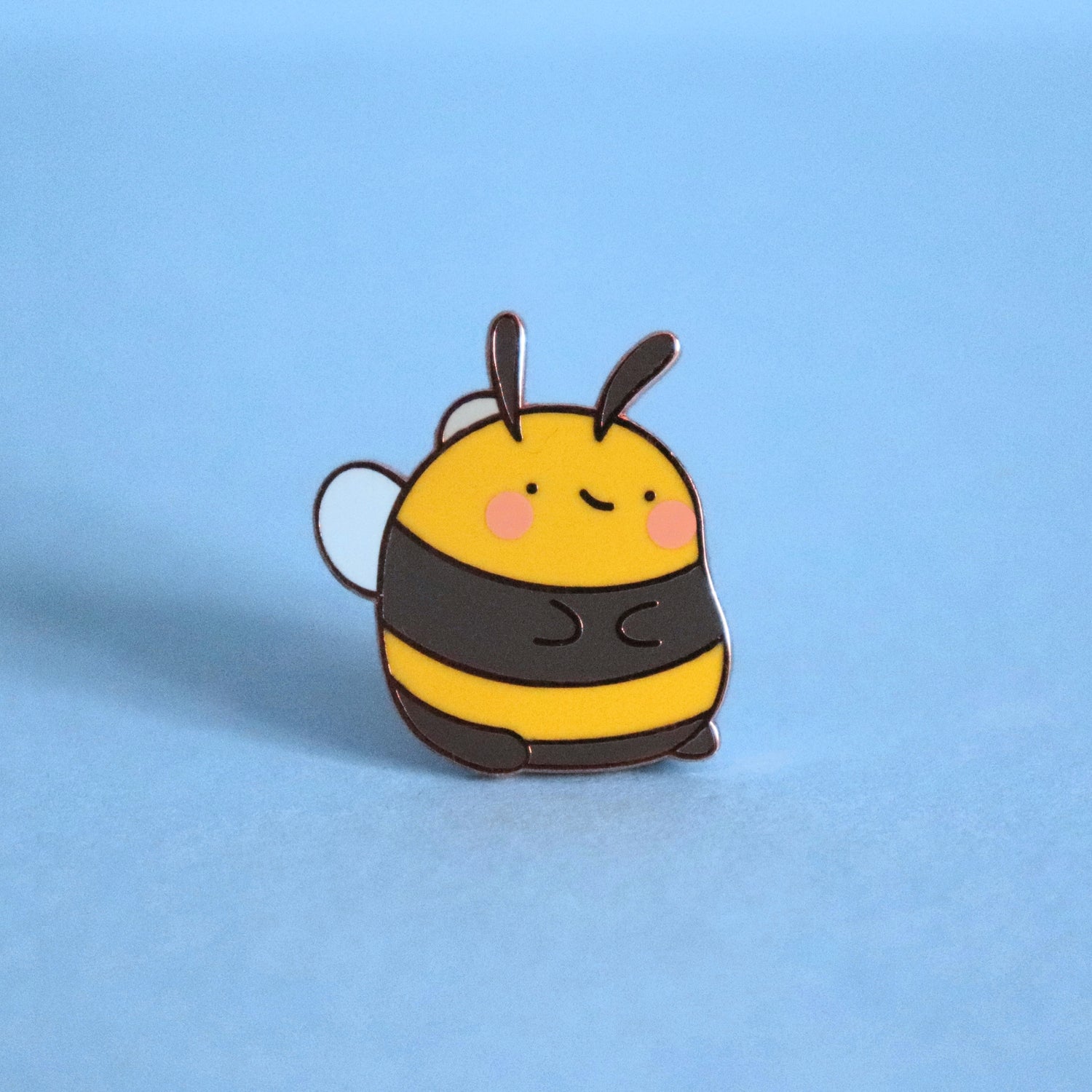 Bee enamel pin on blue background