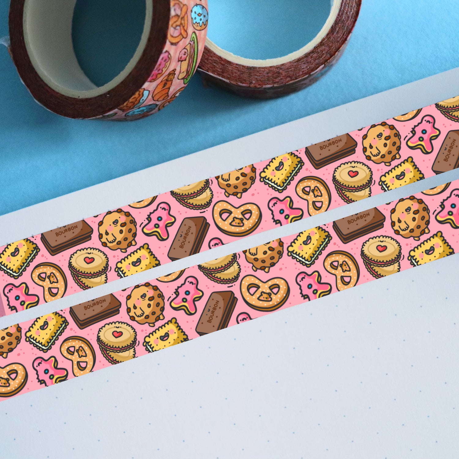 Pink biscuit washi tape on white paper and 2 rolls of washi tape rolls