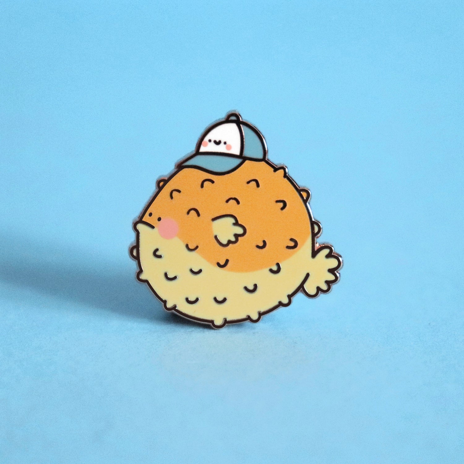 Blowfish enamel pin on blue table