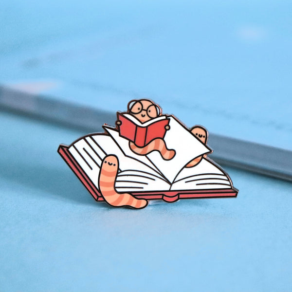 Bookworm enamel pin on blue table