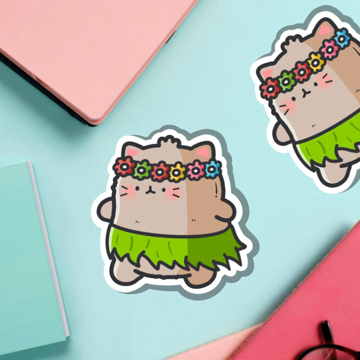 Cat in a grass skirt vinyl sticker on green table with notebooks