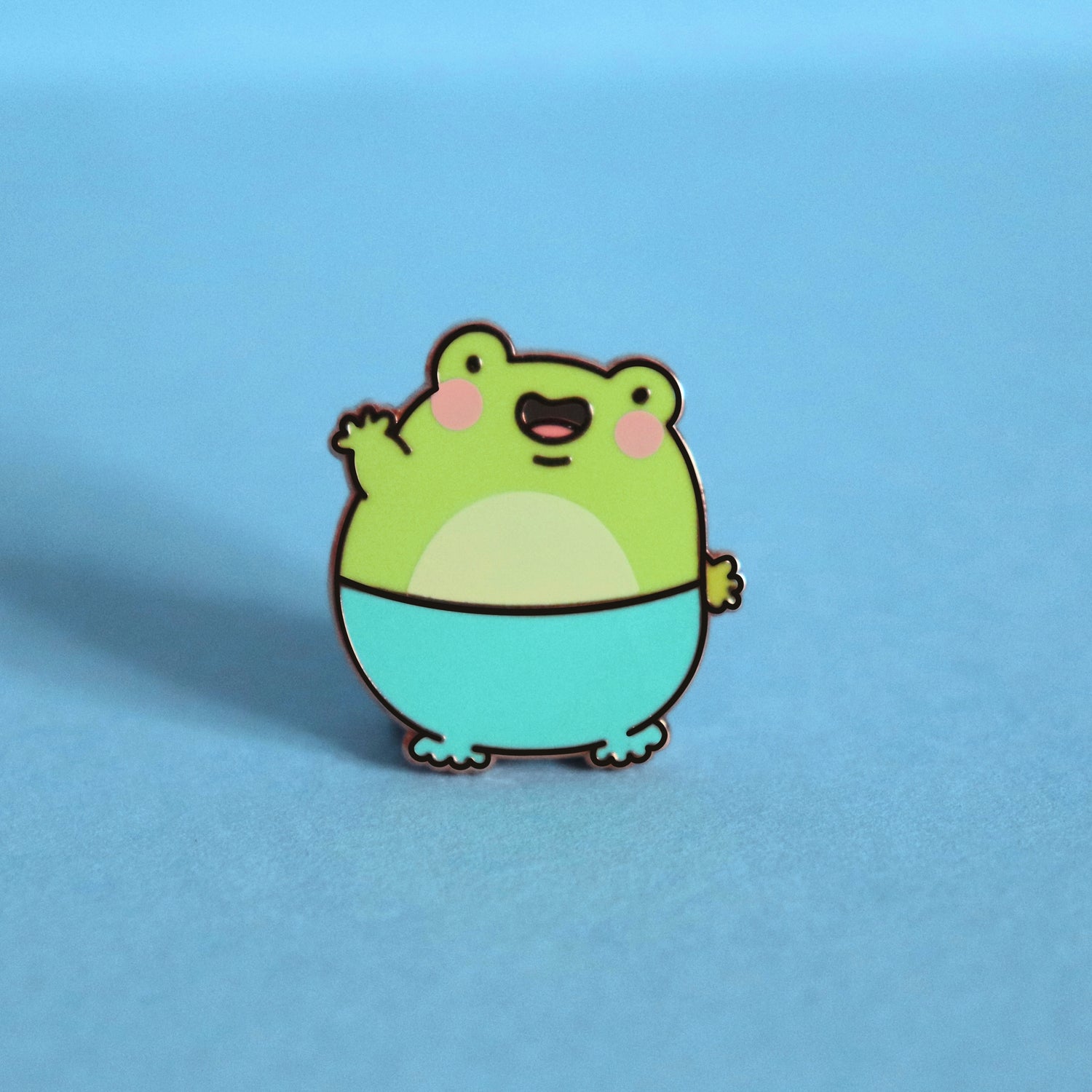 Frog enamel pin on blue background