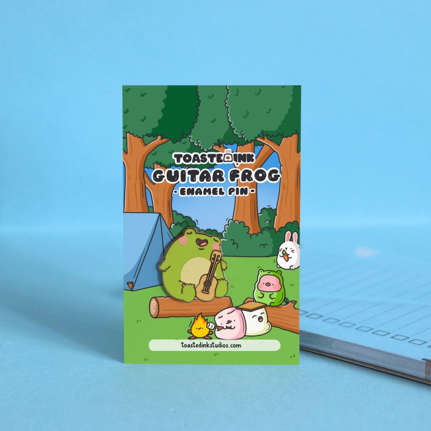 Frog with guitar enamel pin on forest backing card