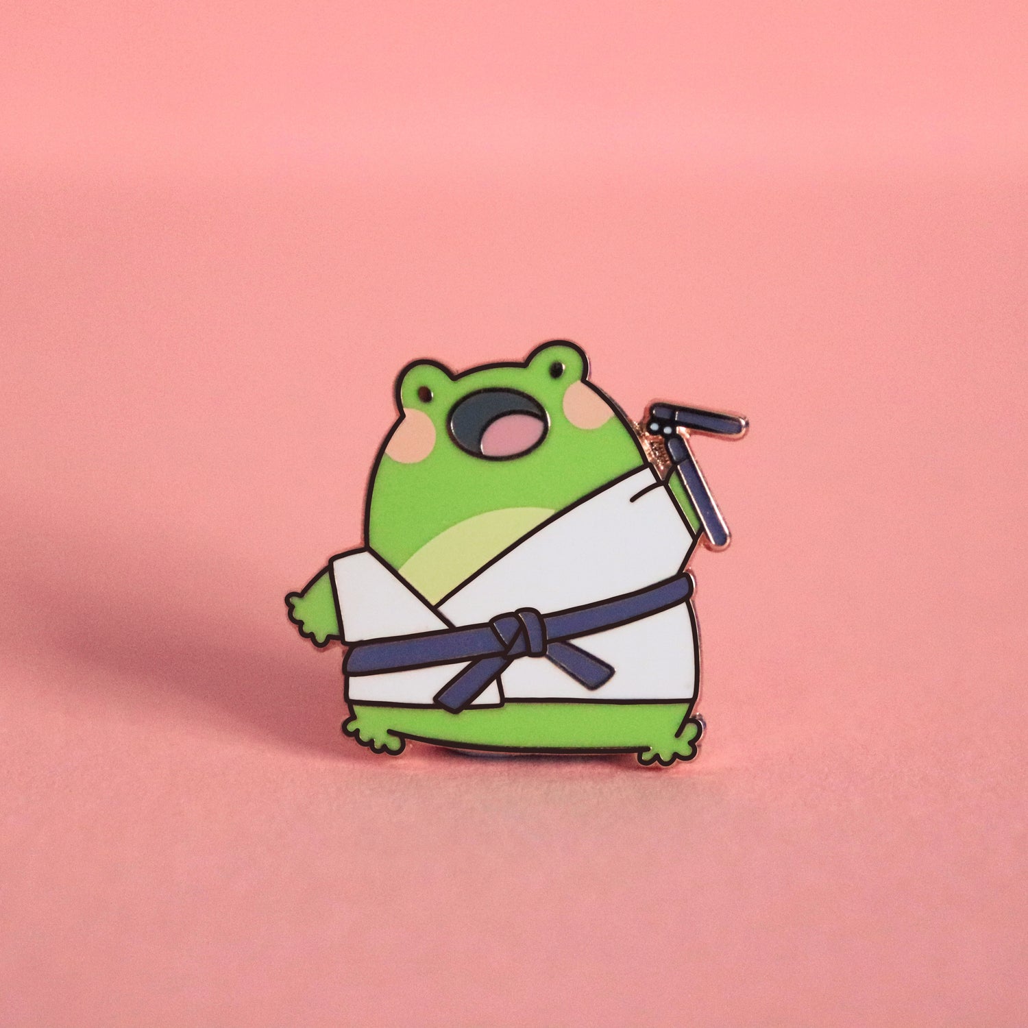 Karate frog enamel pin on pink table