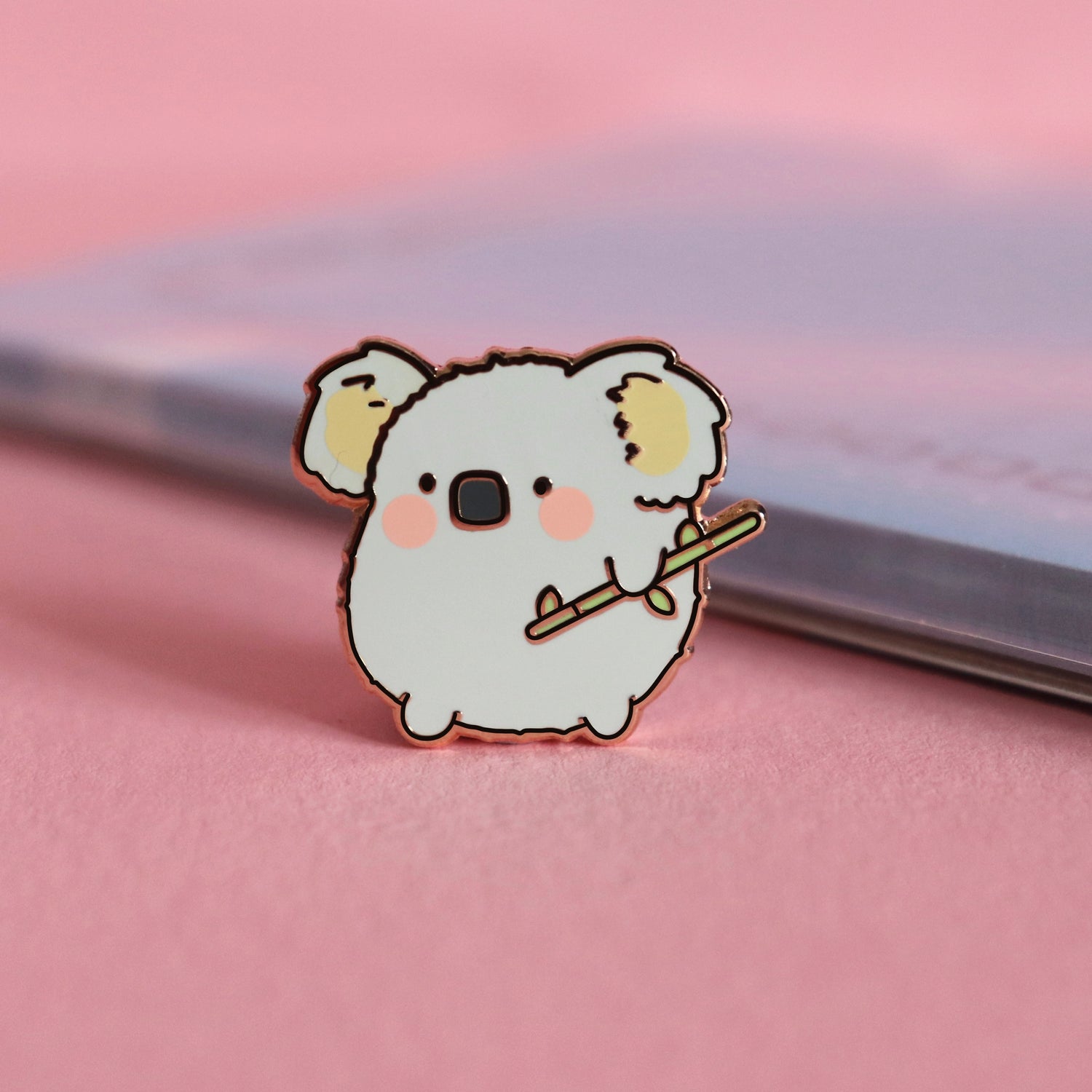 Koala enamel pin on pink table with notepad