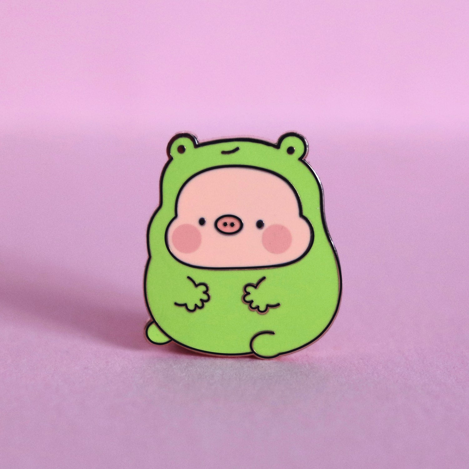 Pig in frog costume enamel pin on pink table