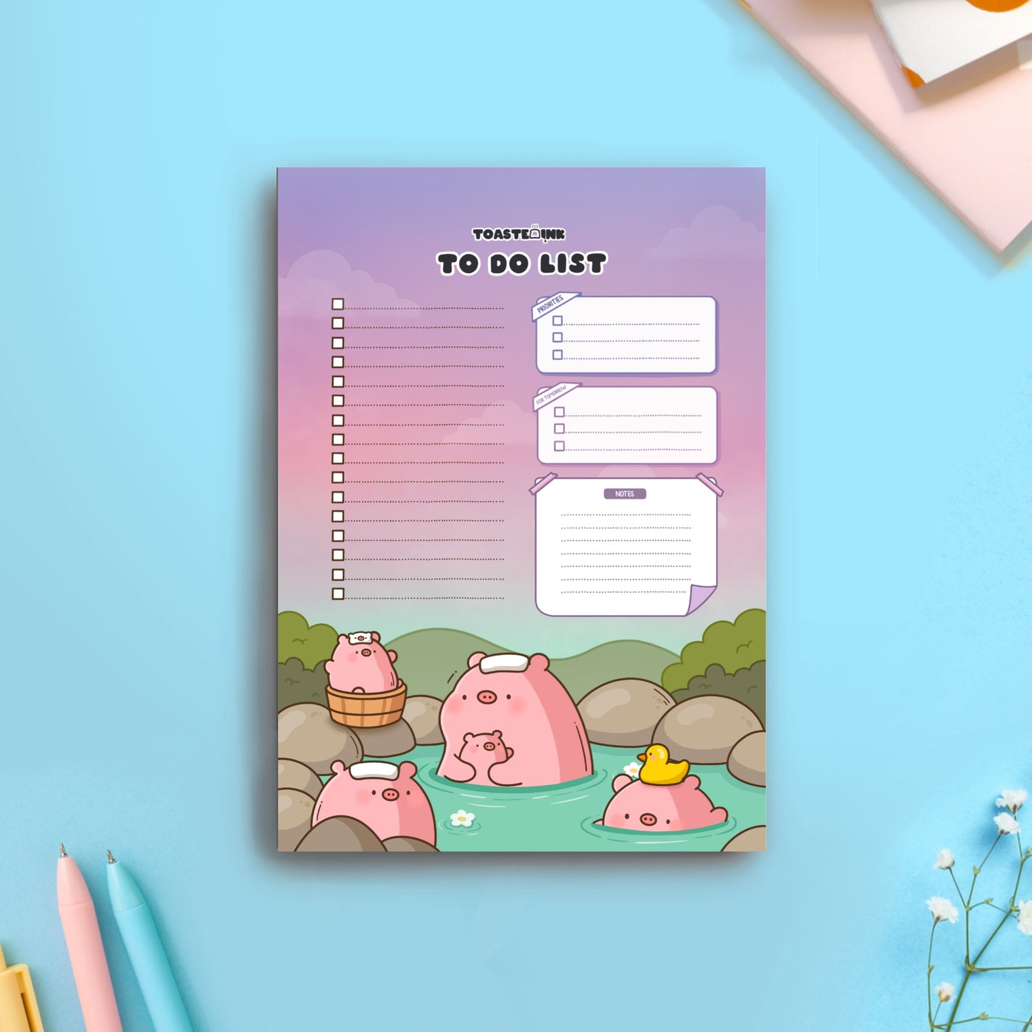 Pig bathing in hot springs to do list pad on blue table with pens and flowers