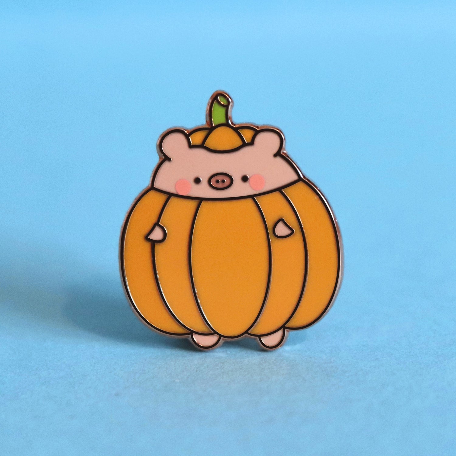pig dressed as pumpkin enamel pin on blue desk