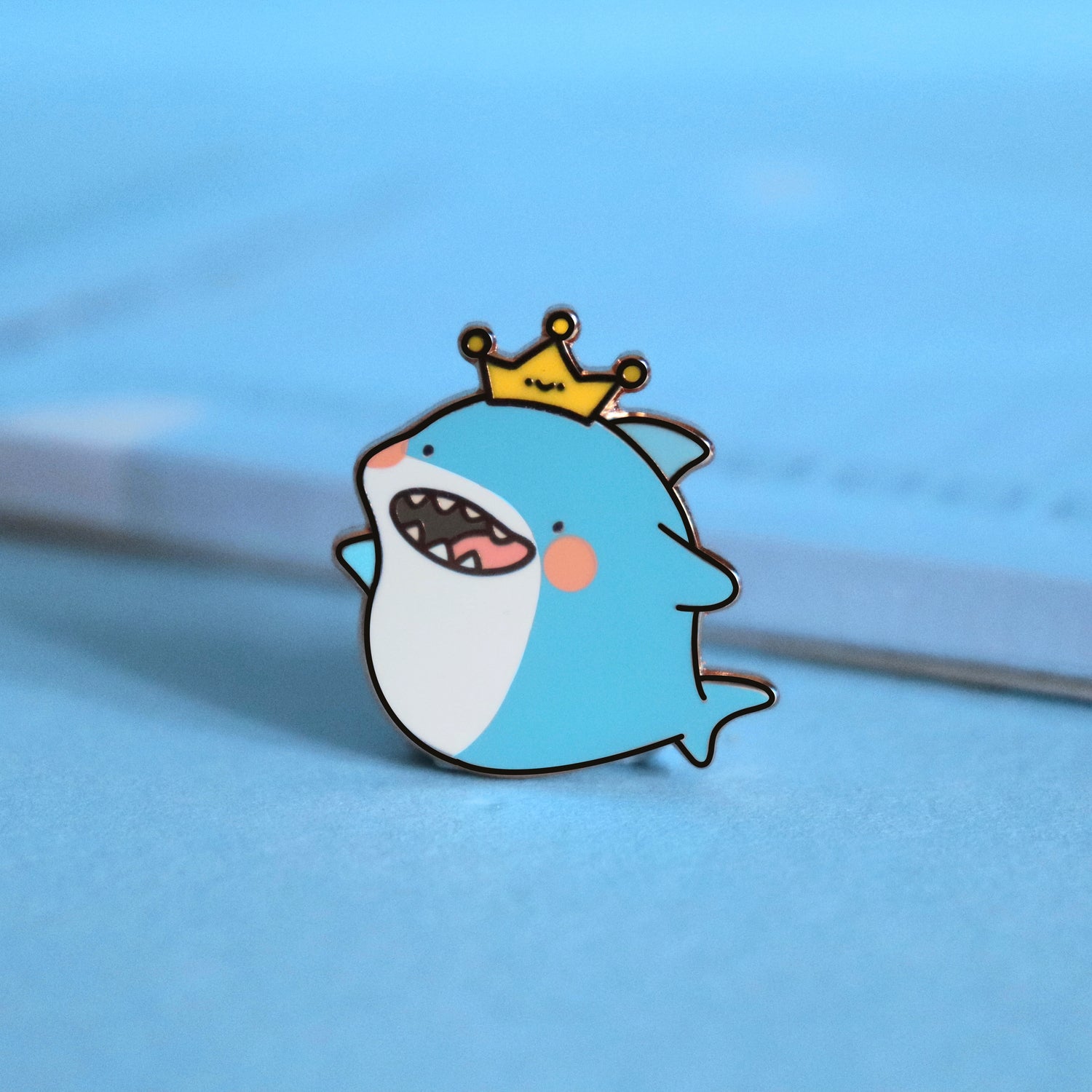 Shark enamel pin on blue table with notepad