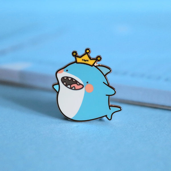 Shark enamel pin on blue table with notepad