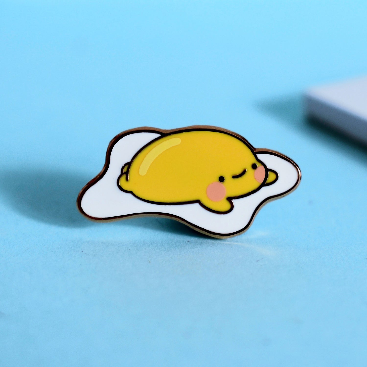 Fried egg enamel pin on blue table