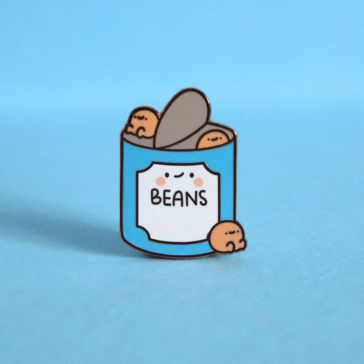 Baked beans enamel pin on blue desk