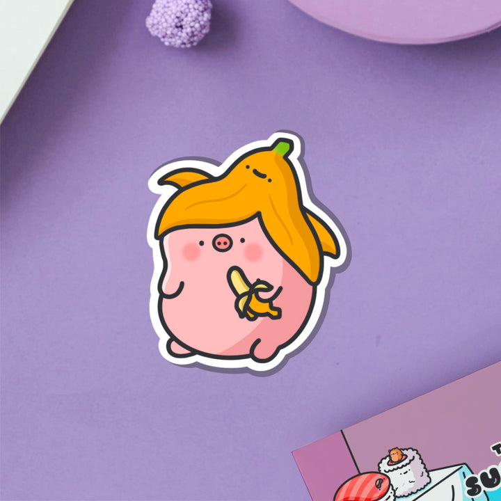 Pig with a banana vinyl sticker on purple table