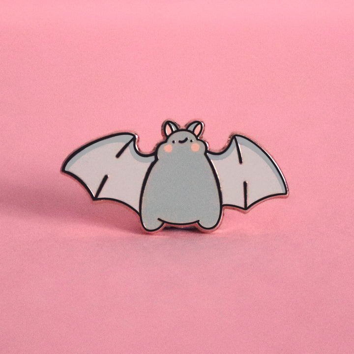 Bat smiling enamel pin on pink table