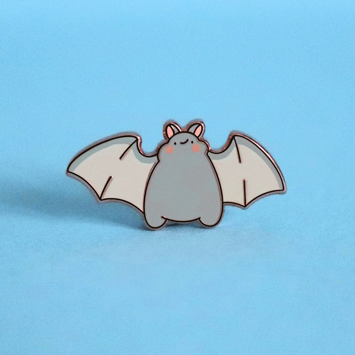 Bat smiling enamel pin on blue desk