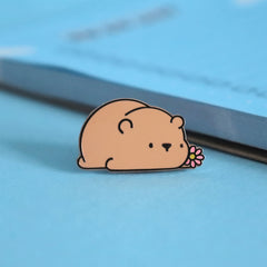Brown bear enamel pin on blue table with notepad