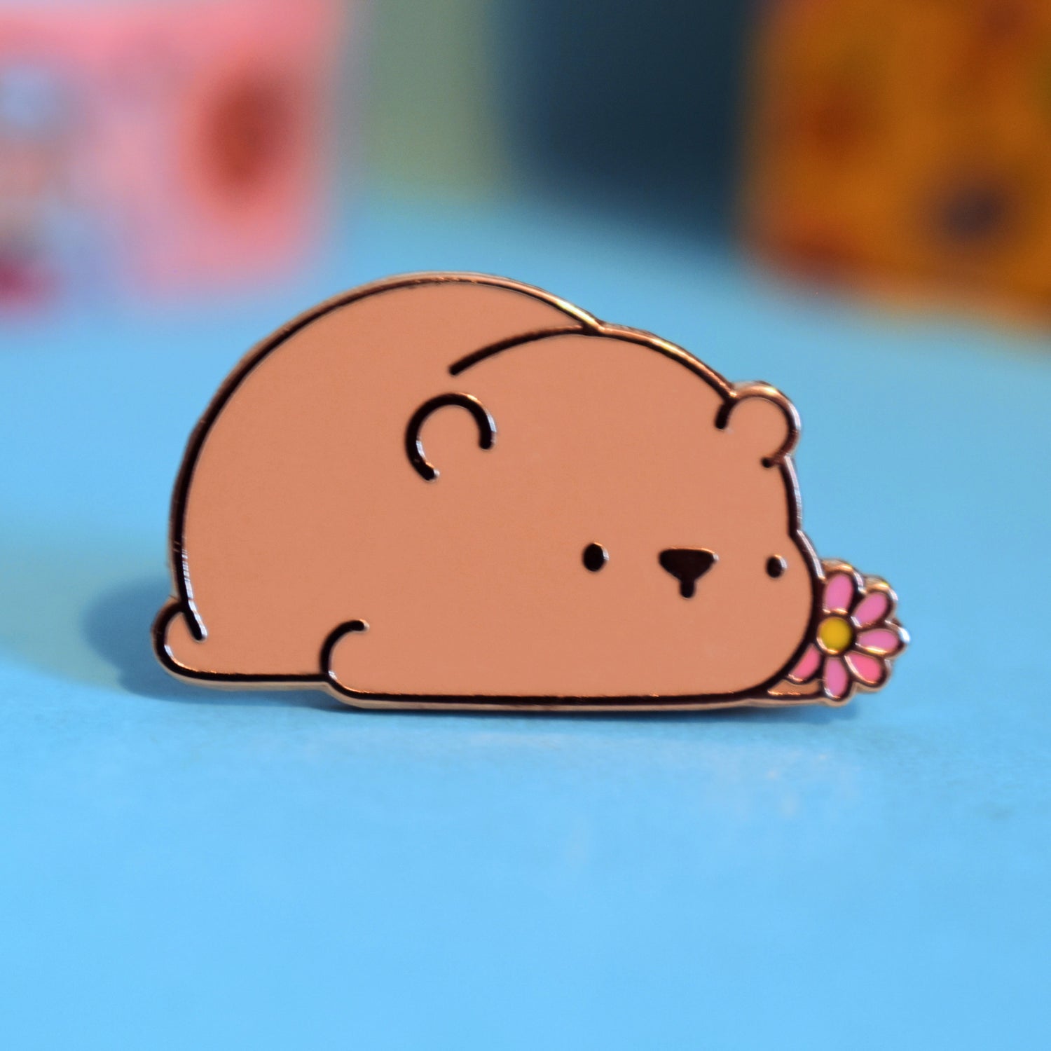 Brown bear enamel pin on blue table