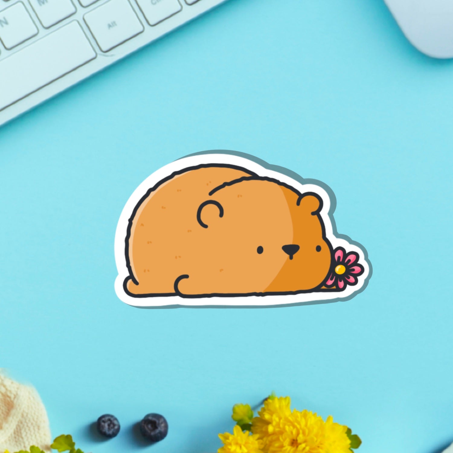 Bear with a flower vinyl sticker on blue table with keyboard