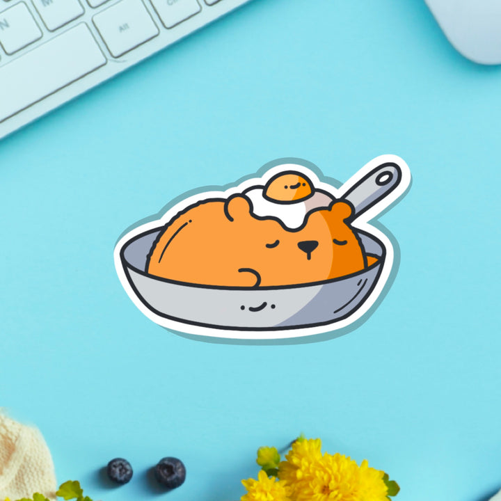 Bear in a frying pan vinyl sticker on blue table with keyboard