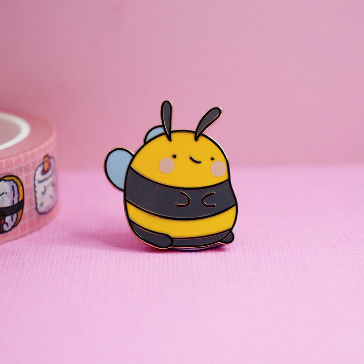 Bee enamel pin on pink table with washi tape