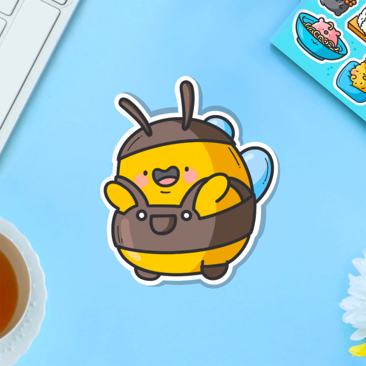 Bee wearing dungarees vinyl sticker on blue table