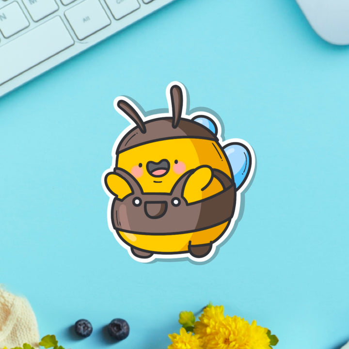 Bee wearing dungarees vinyl sticker on blue table with keyboard