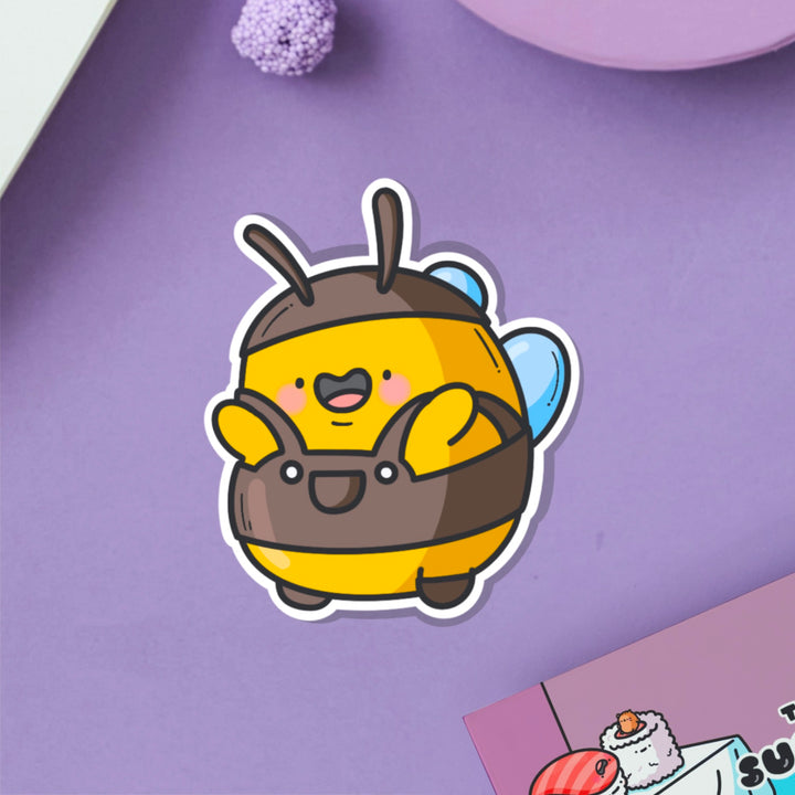 Bee wearing dungarees vinyl sticker on purple table