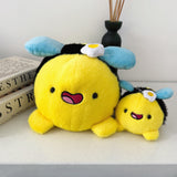 Bee plush and bee keychain plush on white table with books