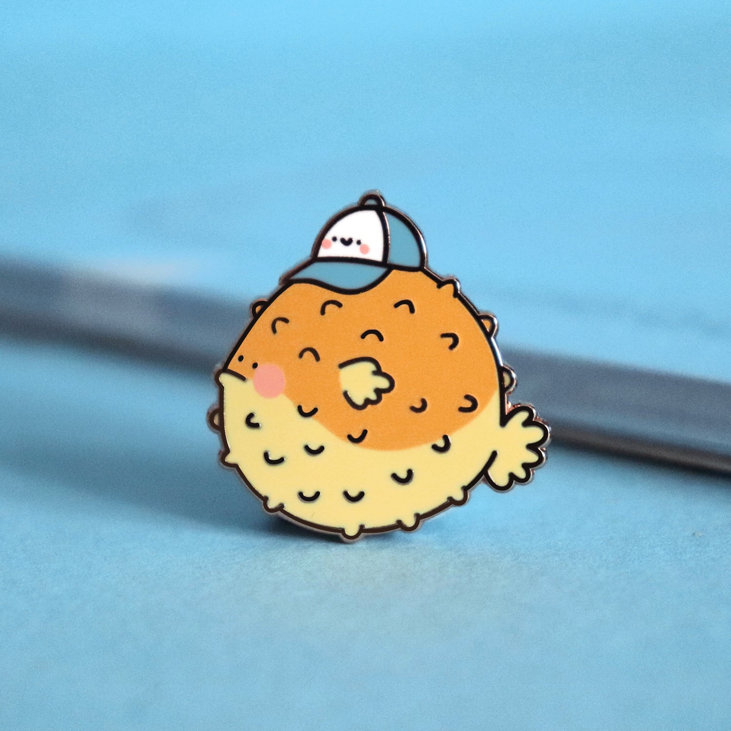 Blowfish enamel pin on blue table