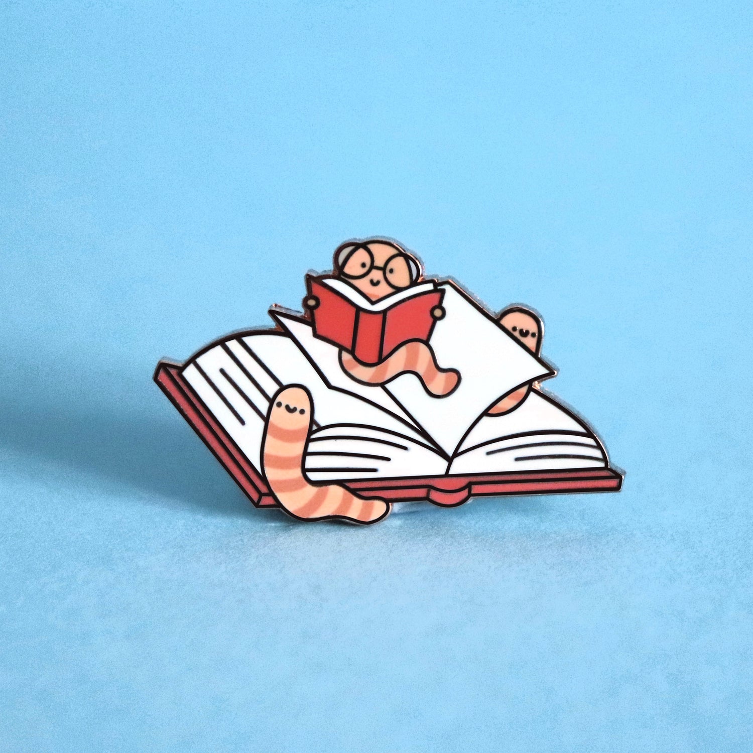 Bookworm enamel pin on blue table