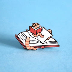 Bookworm enamel pin on blue table