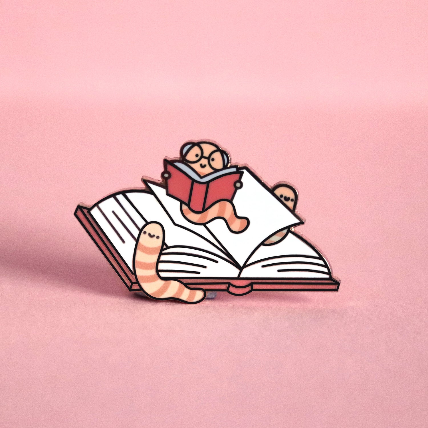 Bookworm enamel pin on pink table