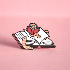 Bookworm enamel pin on pink table
