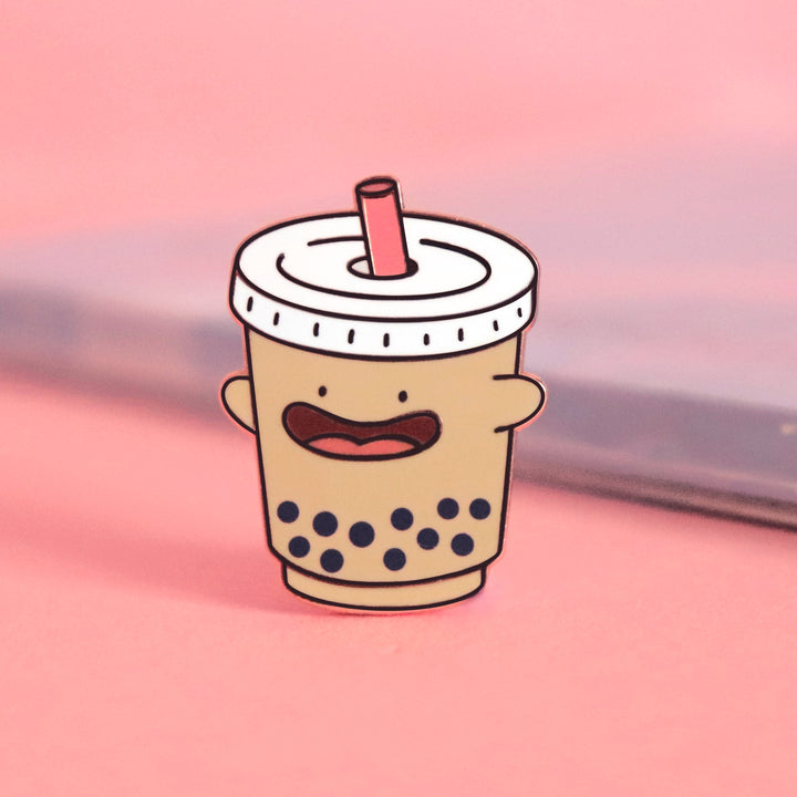 Bubble tea enamel pin on pink desk with notepad