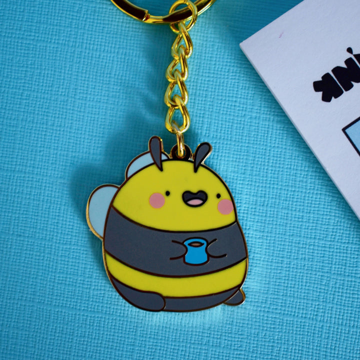 Bumblebee keyring with gold chain on blue table