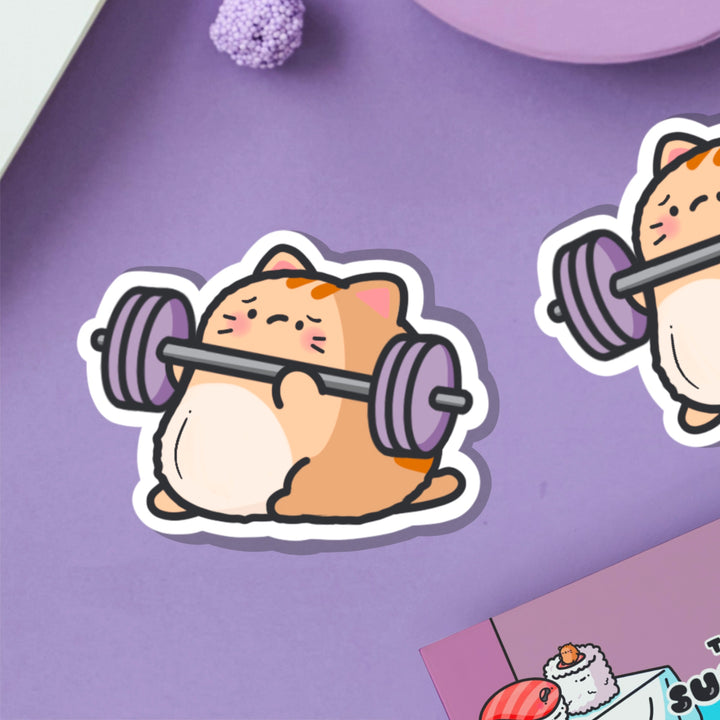 Cat lifting weights vinyl sticker on purple table