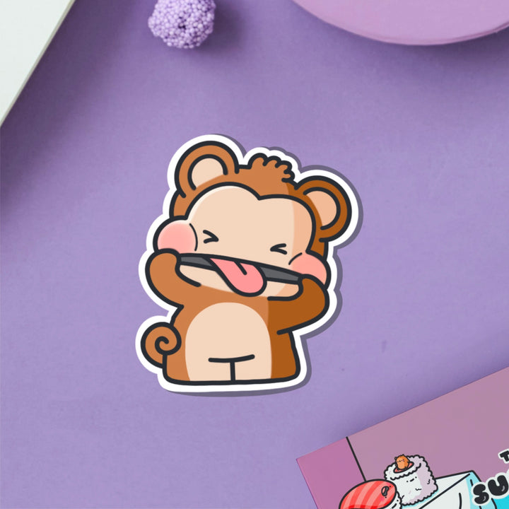 Cheeky monkey vinyl sticker on purple table