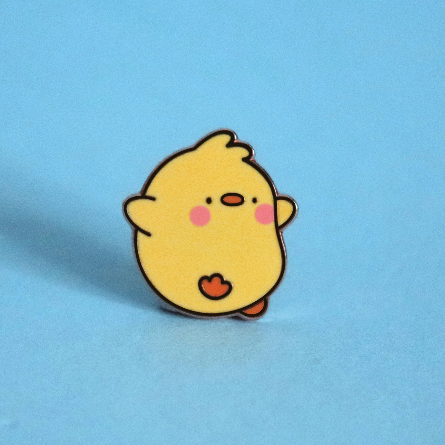 Chick enamel pin on blue desk