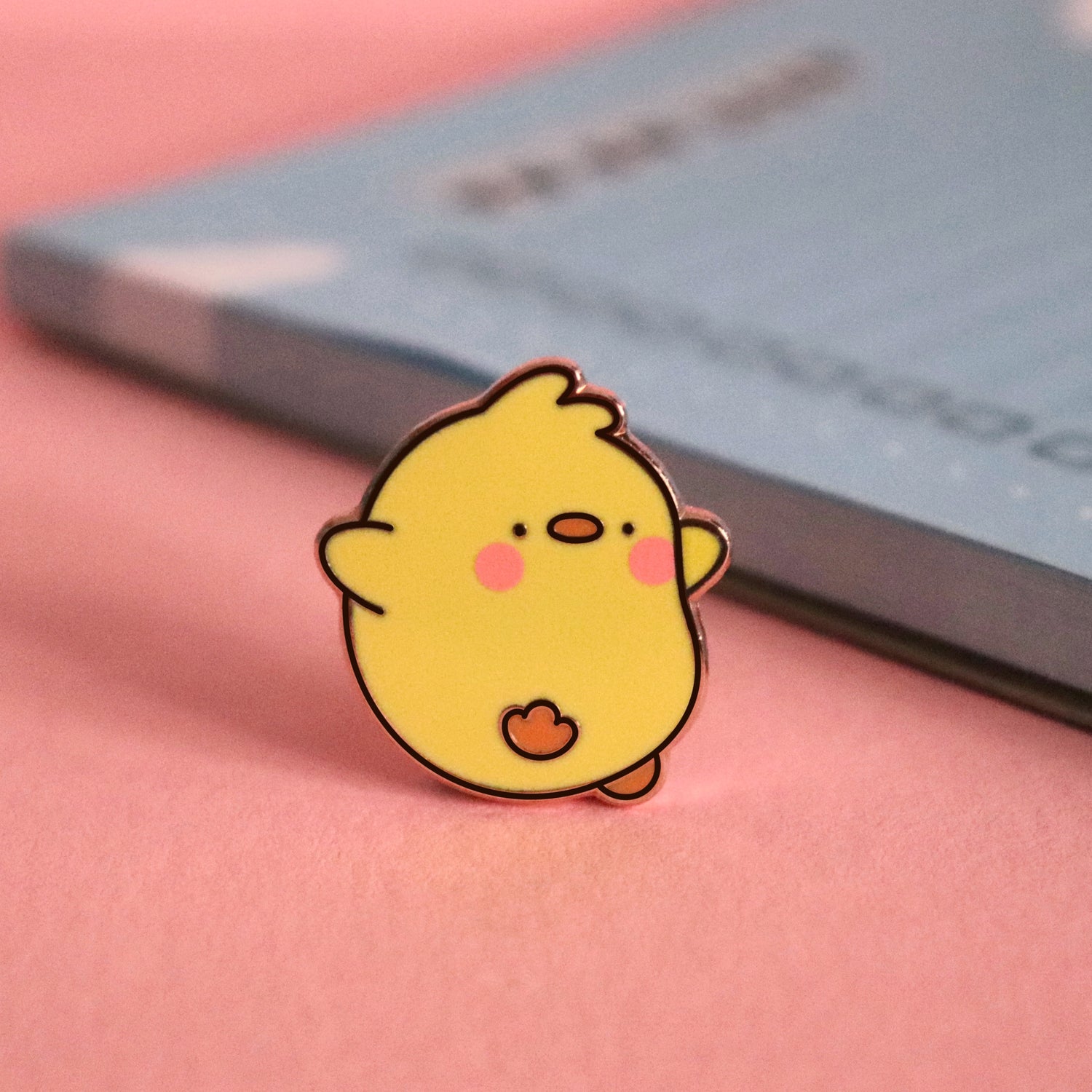 Chick enamel pin on pink table with notepad