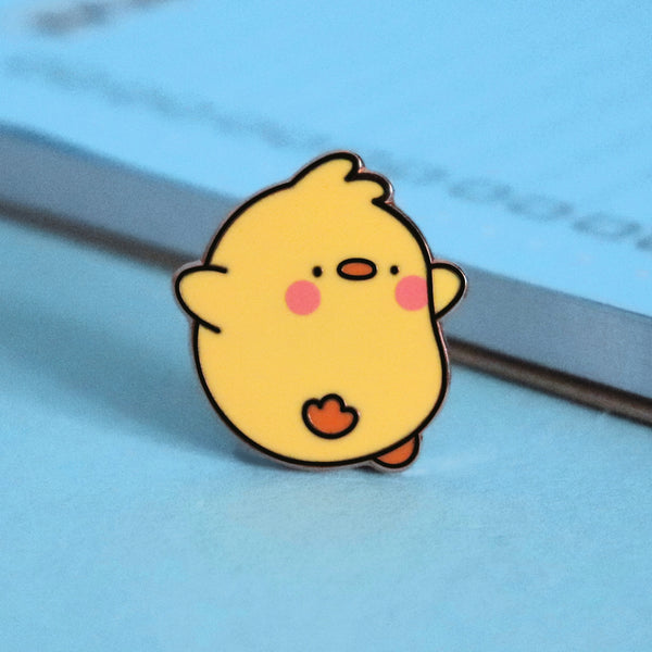 Chick enamel pin on blue table with notepad