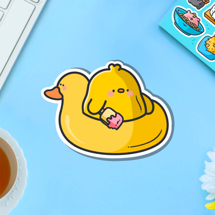 Chick in a rubber duck vinyl sticker on blue table