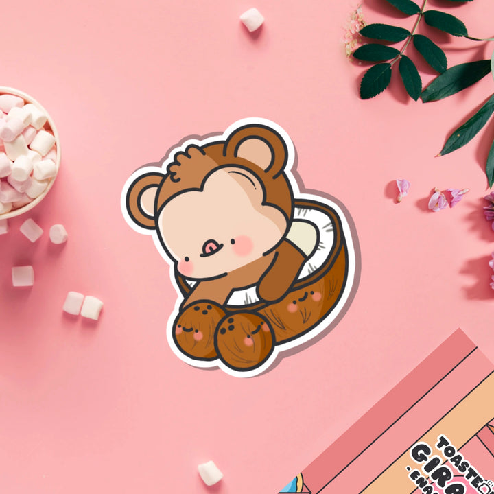 Monkey in a coconut vinyl sticker on pink table