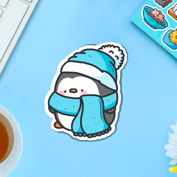 Penguin with scarf vinyl sticker on blue table