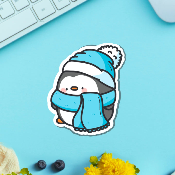 Penguin with scarf vinyl sticker on blue table with keyboard