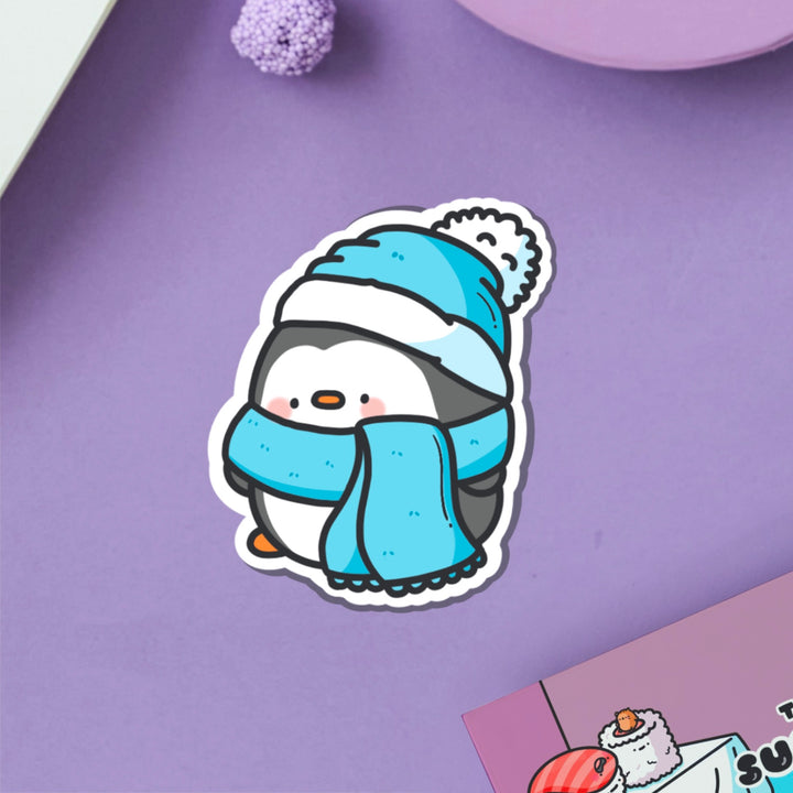 Penguin with scarf vinyl sticker on purple table