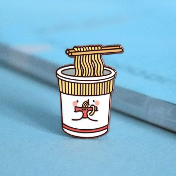 Cup noodles eating bowl of noodles enamel pin on blue table with notepad