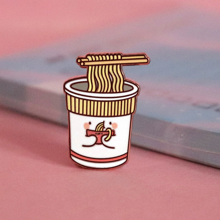 Cup noodles eating bowl of noodles enamel pin on pink table with notepad