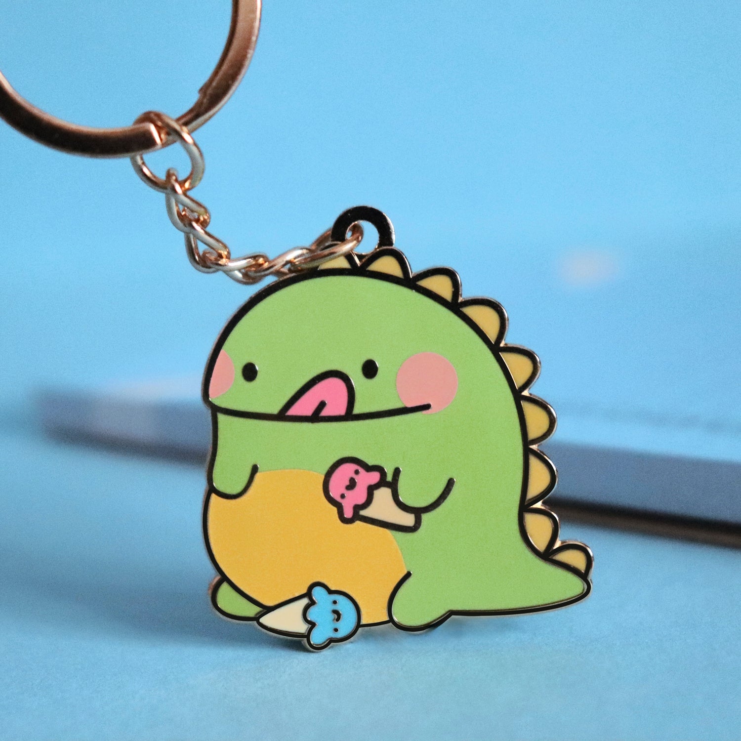 Dinosaur keyring on blue table with notepad