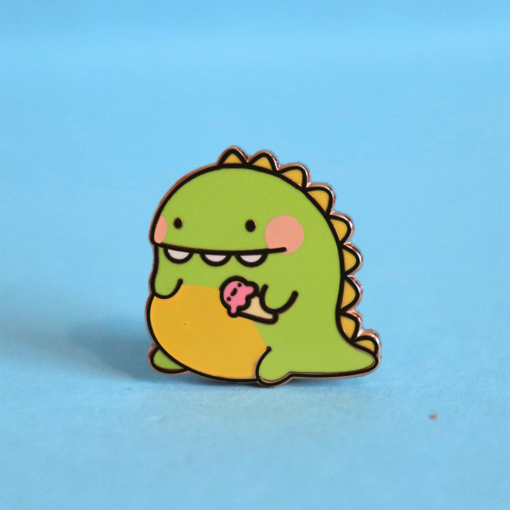 Dinosaur enamel pin on blue desk